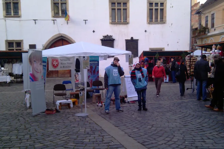 Trei clujeni lustruiesc cizme si pantofi in fata Casei Matei! Din banii stransi vor fi cumpate daruri pentru copii de Mos Nicolae