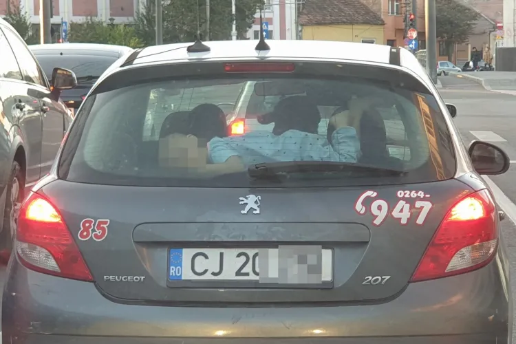 Părinte inconștient la Cluj! Își lasă copilul să stea deasupra porbagajului, sub luneta mașinii - FOTO