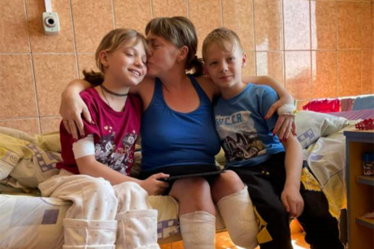 O femeie din Ucraina și fiica sa, rămase invalide după bombardamentele rusești de la gara Kramatorsk. Fratele geamăn al fetiței are grijă de cele două