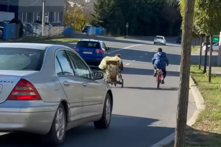 VIDEO ȘOCANT: Doi copii filmați punându-și viața în pericol în trafic, în Cluj. Au improvizat un cărucior de copii tras cu un cablu de o bicicletă